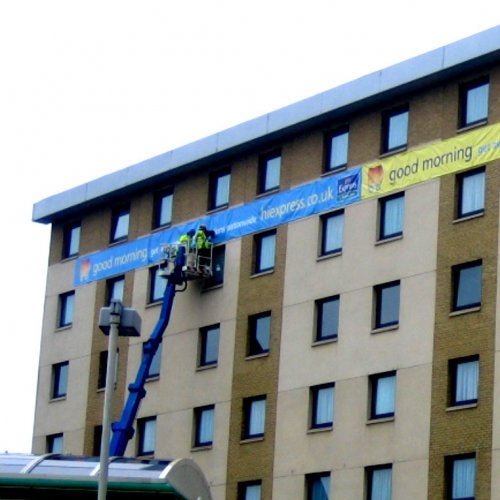 large format vinyl banner being installed on side of hotel